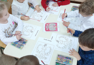 grupa dzieci maluje godło kredkami